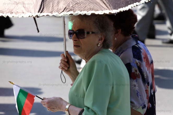 Two women protecting themselves with an umbrella from the scorching heat during the Labor Day demonstration
